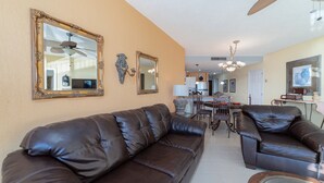 A living room with a brown leather sofa, a dining table with chairs, and a kitchen in the background. - Sonoran Spa E-408 – Inviting Oceanview Condo with Relaxing Coastal Vibes (Puerto Peñasco)