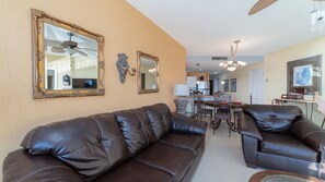 A living room with a brown leather sofa, a dining table with chairs, and a kitchen in the background. - Sonoran Spa E-408 – Inviting Oceanview Condo with Relaxing Coastal Vibes (Puerto Peñasco)