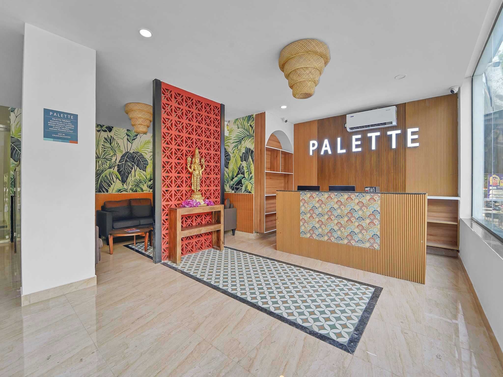 A modern interior with a reception desk labeled 'PALETTE,' a decorative wall with a geometric pattern, and a reception area with a patterned rug.
