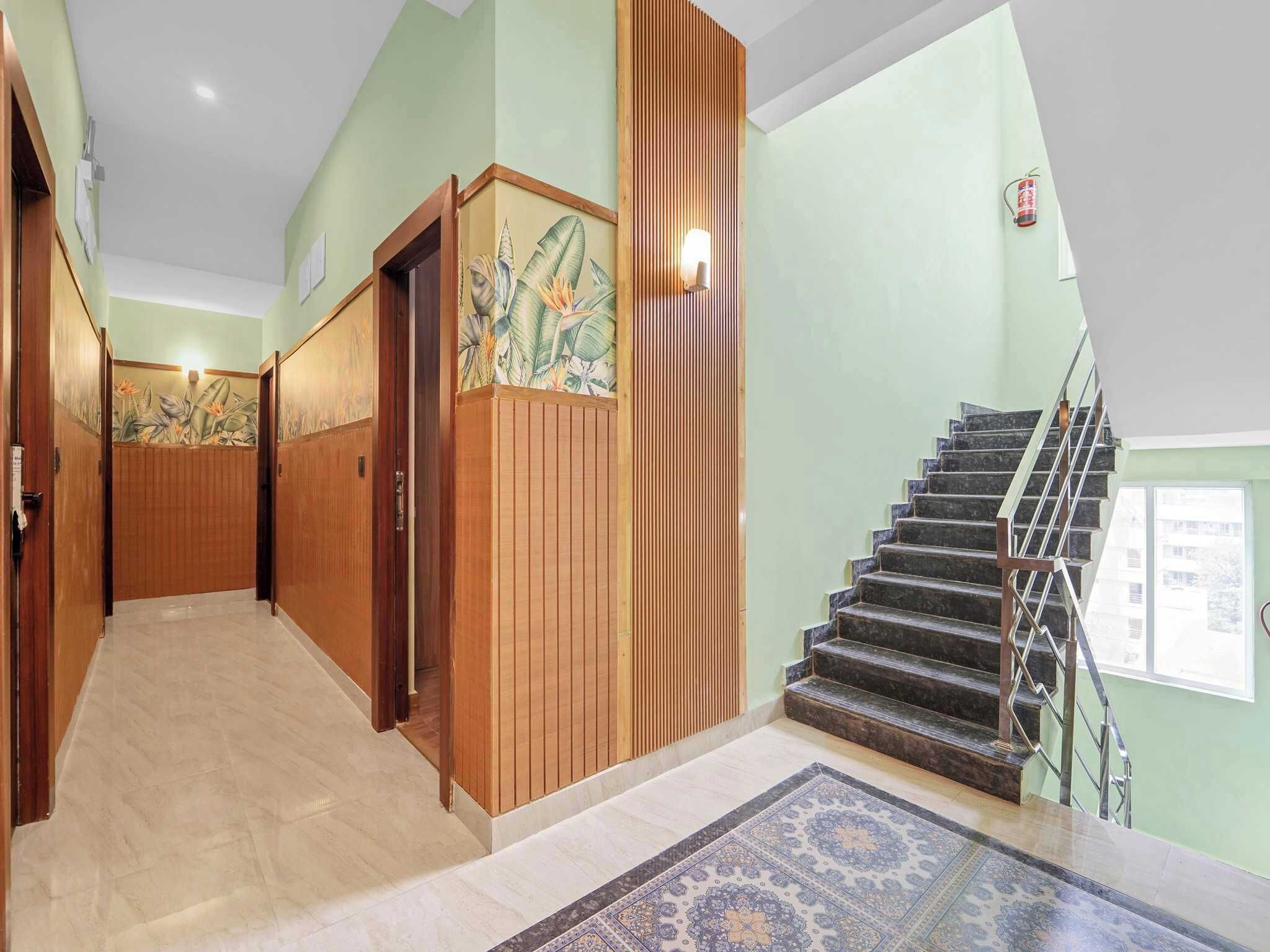 A hallway with wooden doors, a staircase, and a patterned carpet.
