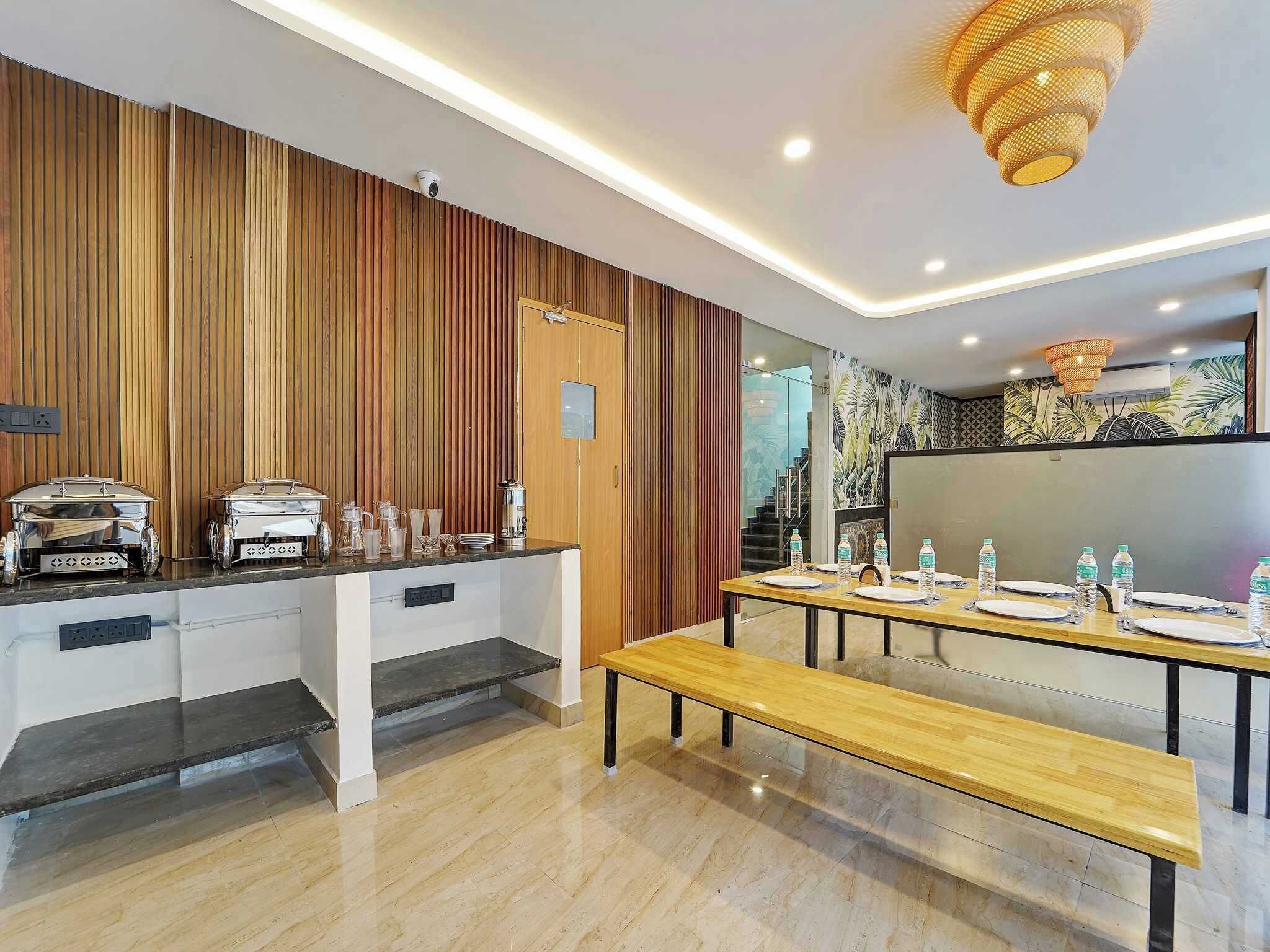 A modern kitchen with a wooden panel wall, a built-in coffee machine, and a long dining table set for a meal.
