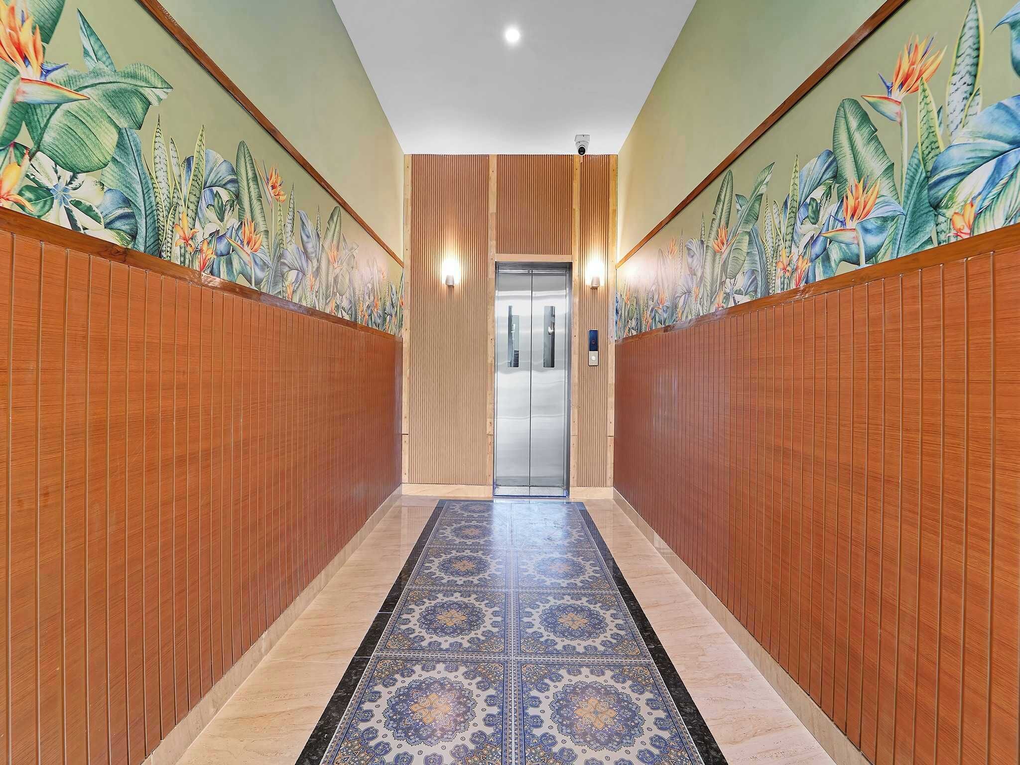 A hallway with wooden paneling, a patterned carpet, and a door leading to an elevator.