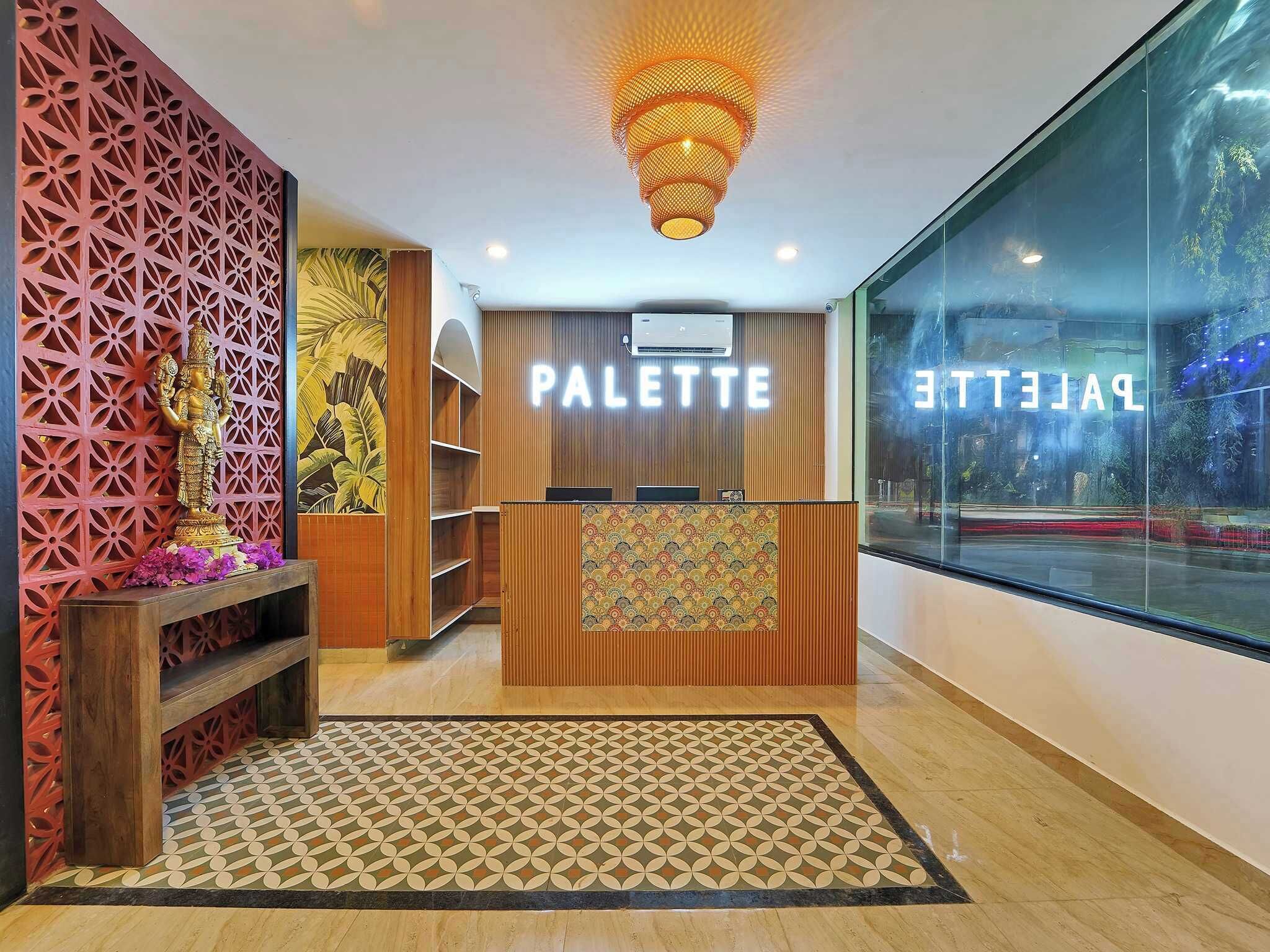 A reception area with a wooden desk, a patterned rug, and a decorative wall with a geometric design.