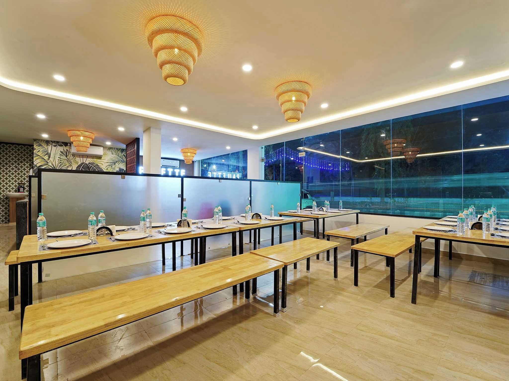 Una sala de conferencias moderna con mesas y bancos de madera, y un amplio ventanal con vistas.