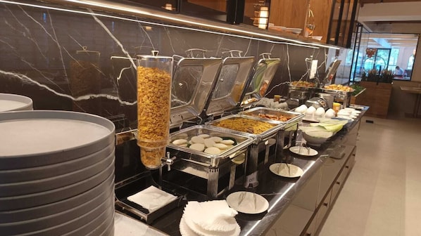 A buffet setup with various food items and utensils. - Hotel Radhe Pride  (Hyderabad)