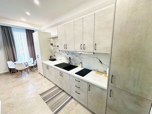 A modern kitchen with grey cabinets, a black sink, and a marble backsplash.
