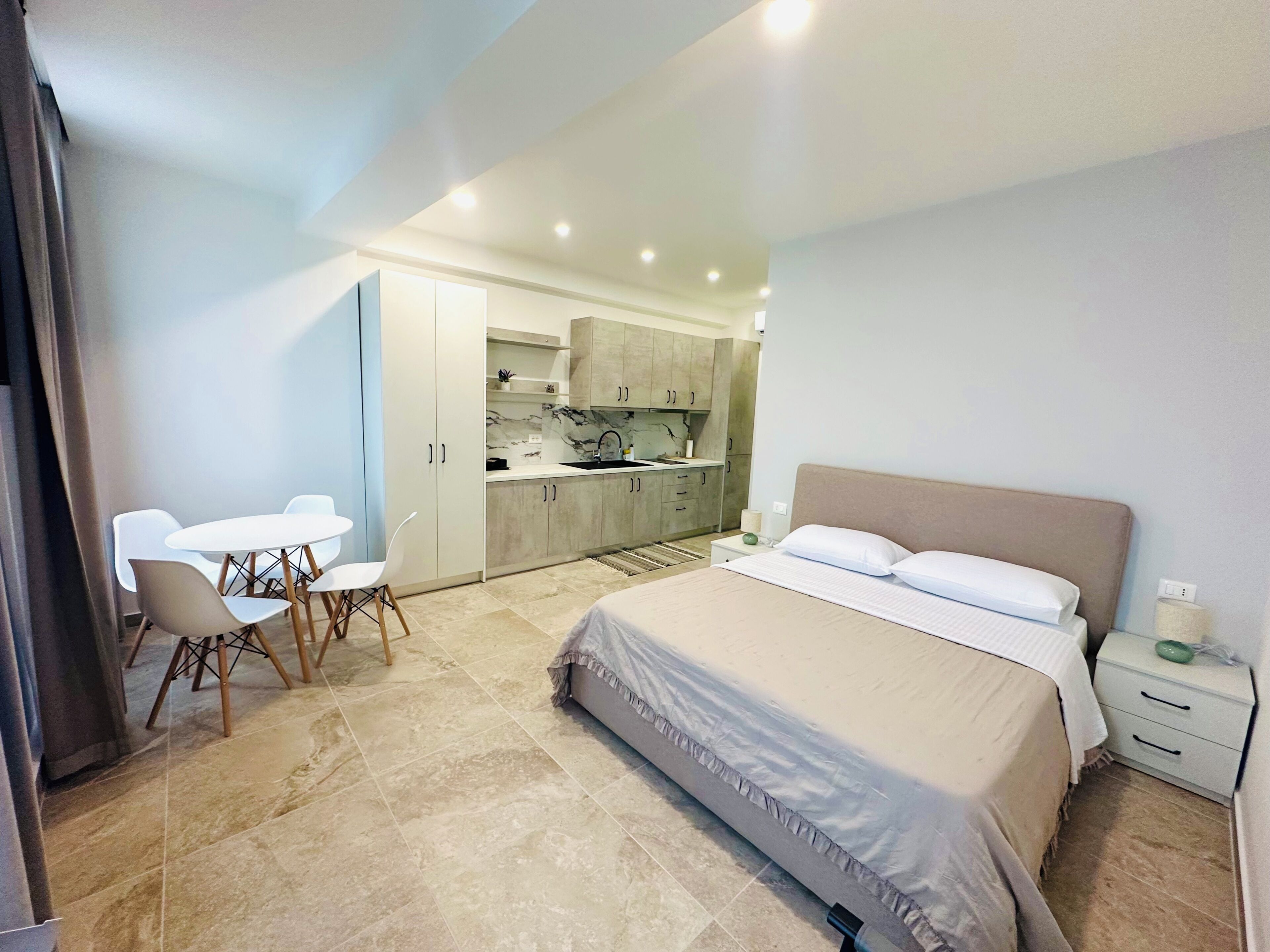 Ein Schlafzimmer mit einem Bett, Nachttischen und Blick in den angrenzenden Küchenbereich.