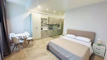 Ein Schlafzimmer mit einem Bett, Nachttischen und Blick in den angrenzenden Küchenbereich.