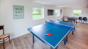 Ein Raum mit zwei Tischtennisplatten, einem Sofa und einem Fernseher.
