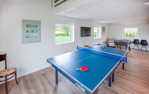 Ein Raum mit zwei Tischtennisplatten, einem Sofa und einem Fernseher.