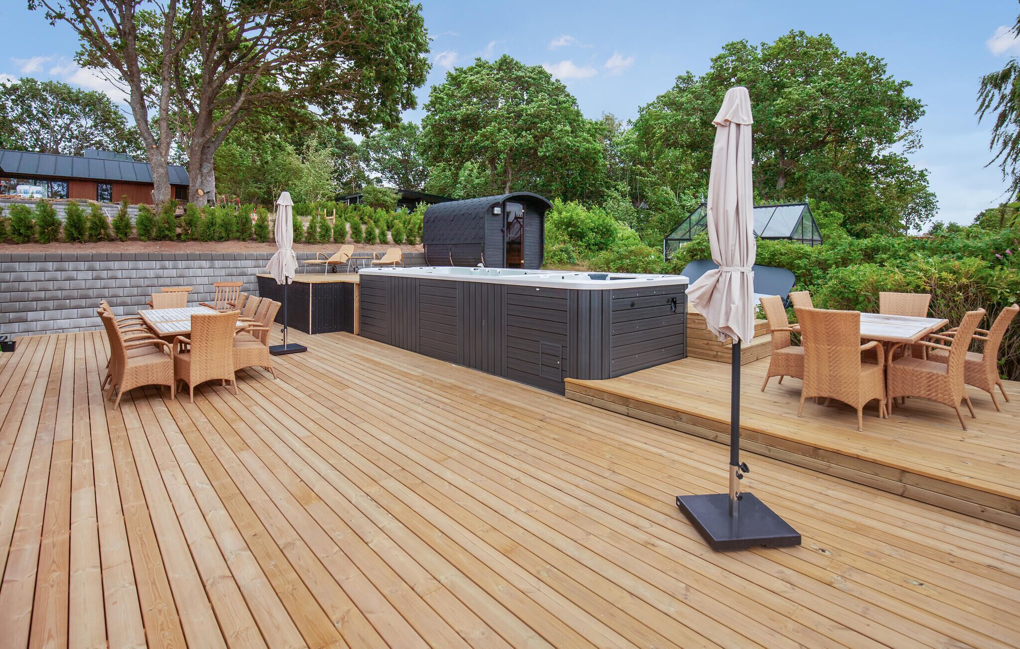 An outdoor deck with a hot tub, wicker furniture, and a barbecue grill.