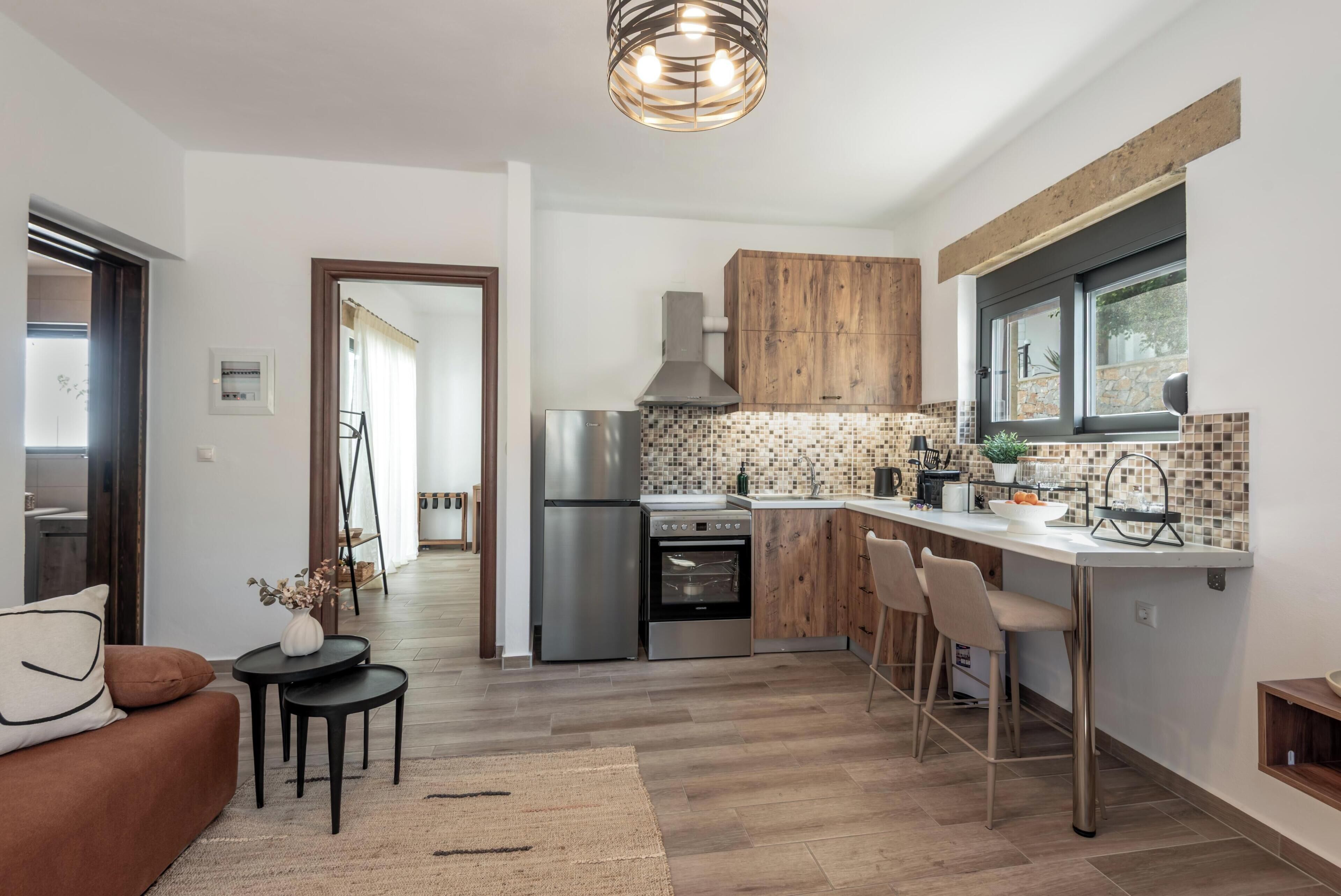 A modern kitchen with a built-in oven, a refrigerator, and a wooden cabinet. There is a dining area with a table and chairs.