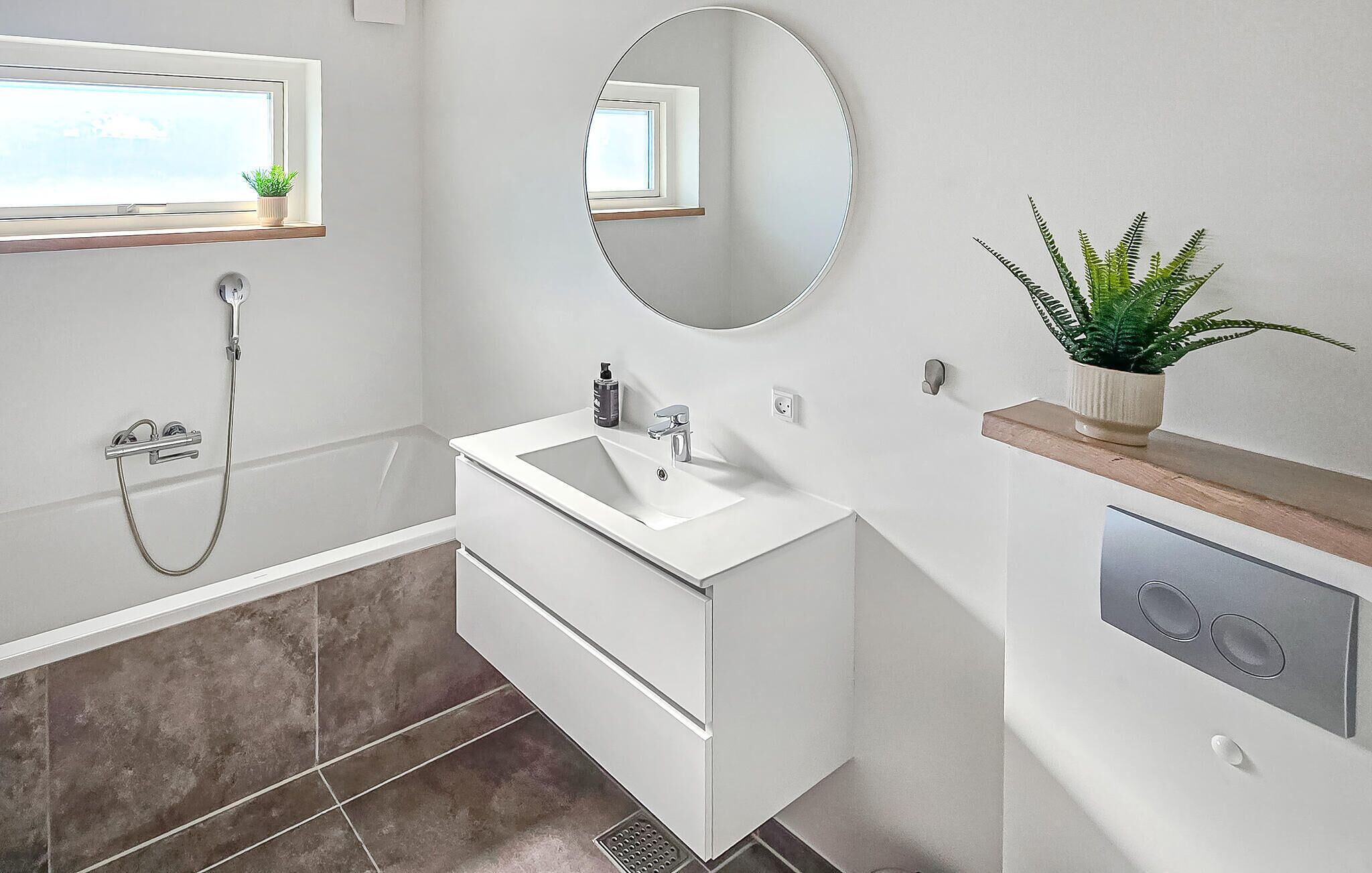 Une salle de bain moderne avec un lavabo blanc, un miroir et une douche.