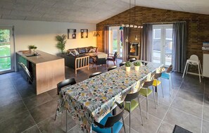 A modern kitchen with a dining area, featuring a long table with chairs, a sofa, and a kitchen counter. - Gorgeous home in Grenaa with sauna (Grenaa)
