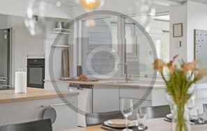 Eine moderne Küche mit Einbauofen, Spüle und Essbereich mit Tisch für zwei Personen.