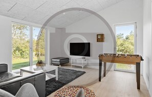 Ein modernes Wohnzimmer mit einer Couch, einem Couchtisch, einem Fernseher und einem Kicker.