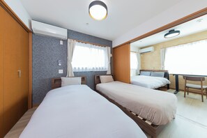 A hotel room with two single beds, a wooden wardrobe, an air conditioning unit, a desk, and a chair. - Casa HM by Tranova (Shinagawa-ku)