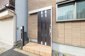 Ein modernes Gebäude mit einer Holzschienelfassade, einer Metall-Rahmentür und einer kleinen Eingangshalle mit einer gefliesten Stufe.