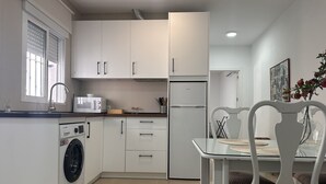 Ett modernt kök med tvättmaskin, mikrovågsugn och kylskåp.