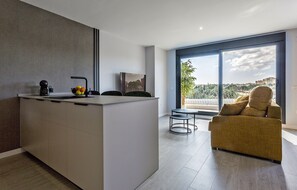 Une cuisine moderne dotée d’un îlot central, d’un coin repas avec un canapé et d’une grande fenêtre offrant une vue sur la ville.