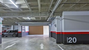 A parking garage with a car parked in one of the bays, directional arrows on the floor, and a wall with the number '120' indicating the bay number. - Sky Garden Jerez - Ole Solutions (Jerez de la Frontera)