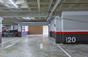 A parking garage with a car parked in one of the bays, directional arrows on the floor, and a wall with the number '120' indicating the bay number. - Sky Garden Jerez - Ole Solutions (Jerez de la Frontera)
