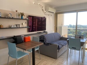 Ein modernes Wohnzimmer mit Sofa, Esstisch, Stühlen, Fernseher und einem Balkon mit Blick.