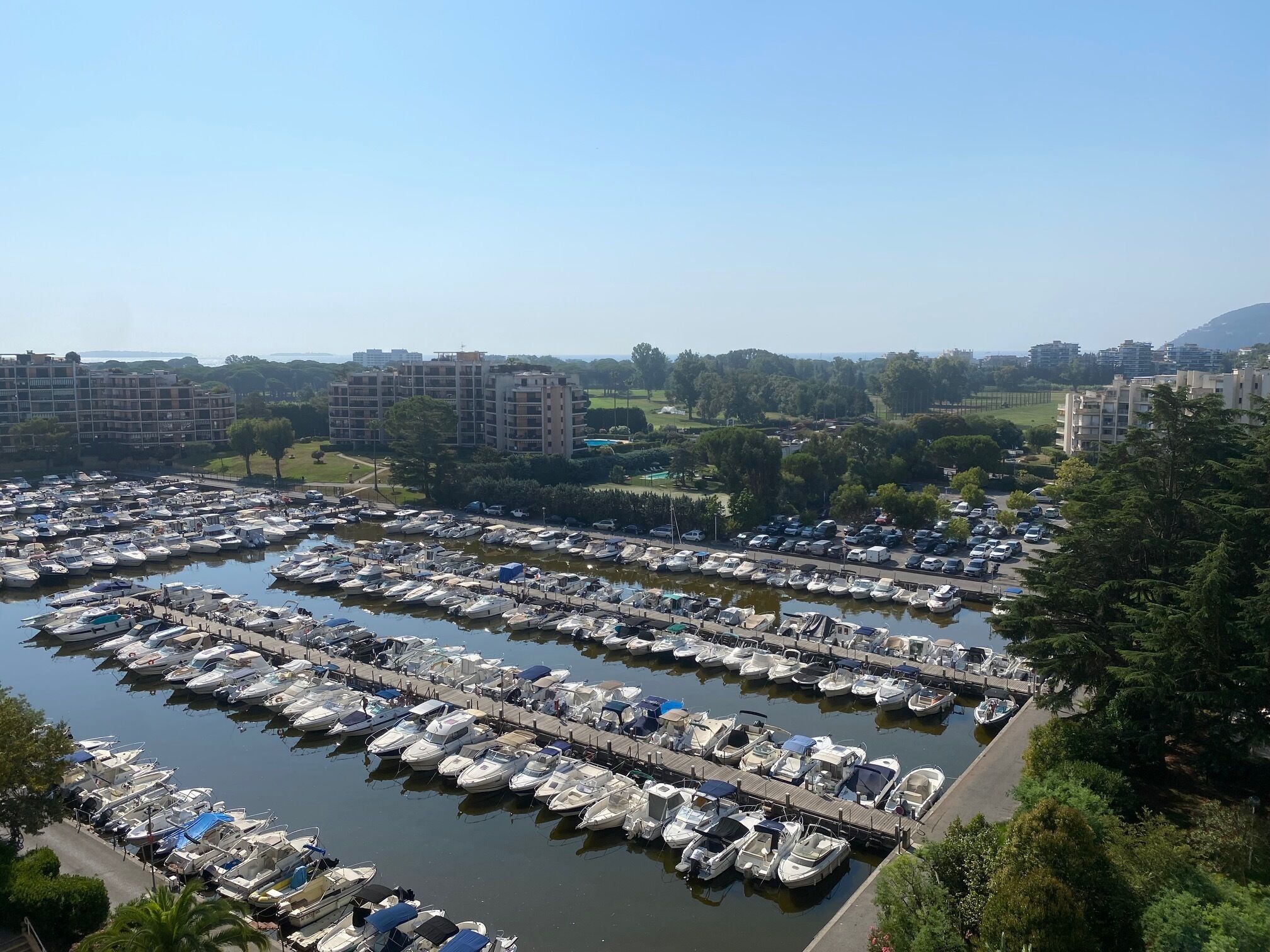 Un port de plaisance où de nombreux bateaux sont amarrés, entouré de bâtiments résidentiels et de verdure.