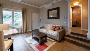 Ein Wohnzimmer mit Sofa, Couchtisch und Blick ins Freie.