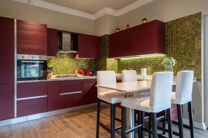 Una cocina moderna con armarios rojos, una estufa de acero inoxidable y un salpicadero de azulejos verdes.