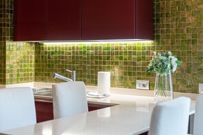 A modern kitchen with a white countertop, stainless steel faucet, and a green mosaic backsplash. - Limonta Breathless View by Wonderful Italy (Limonta)