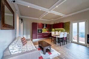 A modern kitchen with red cabinets, a dining area with a white table and chairs, and a large window overlooking a snowy landscape. - Limonta Breathless View by Wonderful Italy (Limonta)