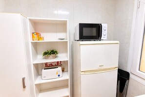 A compact kitchen with a white refrigerator, a microwave, and a toaster on a shelf. - 1A174 Central Apartment in Gijón (Gijón)