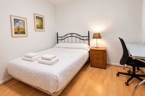 A single bed with white linens, a bedside table with a lamp, a chair, and two framed pictures on the wall. - 1A174 Central Apartment in Gijón (Gijón)