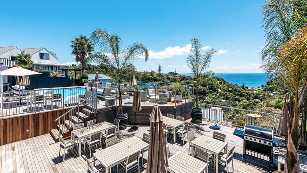 Eine Dachterrasse mit Pool, Sitzgelegenheiten im Freien und Blick aufs Meer.
