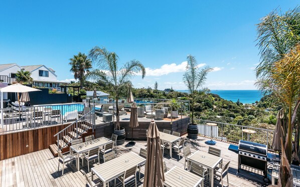 A rooftop deck with a pool, outdoor seating, and a view of the ocean.