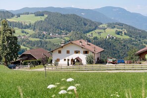 A rural house with a sloped roof, a fenced yard, and a view of the surrounding countryside. - Gatterpunerhof "Völs" Farmhouse with Mountain View, Shared Terrace and Wi-Fi (Völs am Schlern)