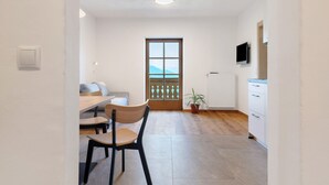 Una cocina moderna con comedor, suelo de madera, planta en maceta y vistas por una ventana.