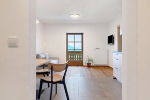 A modern kitchen with a dining area, wooden flooring, a potted plant, and a view through a window. - Gatterpunerhof "Völs" Farmhouse with Mountain View, Shared Terrace and Wi-Fi (Völs am Schlern)