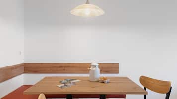 A wooden table with a white pitcher and eggs, a wooden chair, and a hanging light fixture.