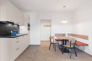 Eine moderne Küche mit Essbereich, ausgestattet mit einem Backofen, einer Kaffeemaschine und einer Pendelleuchte.