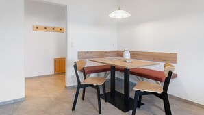 Un comedor con una mesa, sillas, un banco, una lámpara colgante y un panel de madera en la pared.