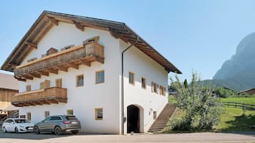 A two-story building with a balcony, a staircase, and a car parked in front.