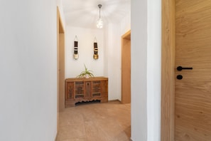 A hallway with a wooden door, a light fixture, and a cabinet with a plant. - Gatterpunerhof "Völs" Farmhouse with Mountain View, Shared Terrace and Wi-Fi (Völs am Schlern)