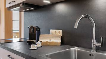 A modern kitchen with a stainless steel sink, a coffee maker, and a box of Nespresso capsules.
