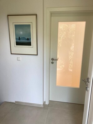 Una puerta con vidrio esmerilado, un cuadro en la pared y un interruptor de luz.