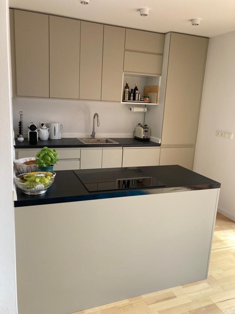 A modern kitchen with a central island, a built-in sink, and a countertop with various kitchen items.