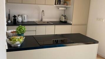 A modern kitchen with a central island, a built-in sink, and a countertop with various kitchen items.