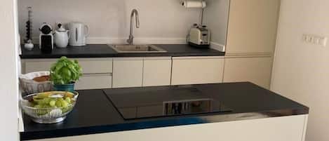 A modern kitchen with a central island, a built-in sink, and a countertop with various kitchen items.