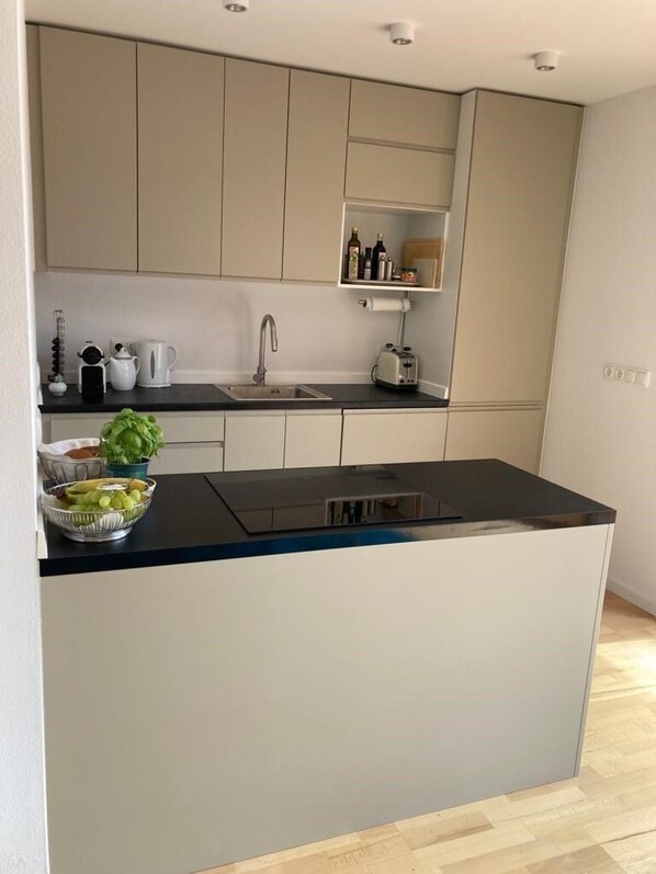 A modern kitchen with a central island, a built-in sink, and a countertop with various kitchen items.